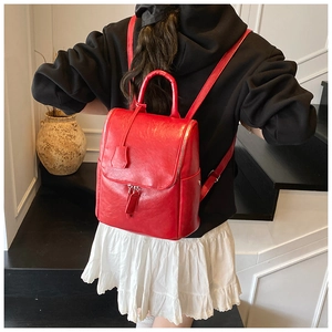 Detailed back view of a vibrant red leather backpack on a model showing daily use size
