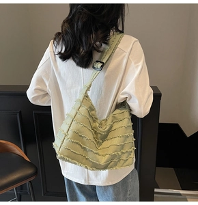 Detail view of large light green canvas tote bag with fringed edges on a model