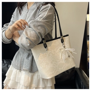 Detail of white snakeskin tote bag with pearl lace bow charm and silver hardware