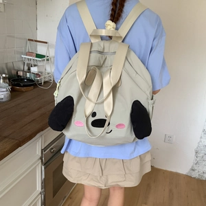 Close-up of a cute cartoon dog nylon backpack featuring 3D long black ears on a beige bag