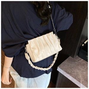 Detail view of beige ruched cloud bag with woven strap and silver metal chain strap