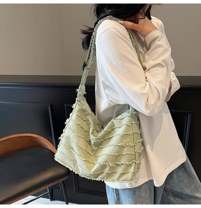 Detail of light green canvas tote bag with retro fringe textures and adjustable strap