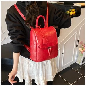 Red PU leather backpack for women with silver metal zippers shown on model's back