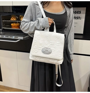 Detail der weißen 3D-Jacquard-Nylontasche mit einer silbernen ovalen Logo-Plakette