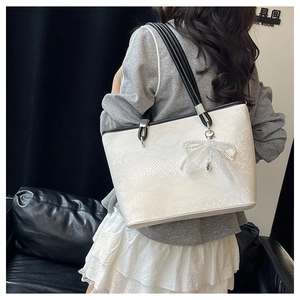 Detail view of snakeskin pattern leather tote bag with pearl lace bow accessory
