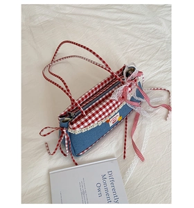Detail of blue denim tote bag with red gingham handles, lace trim and bow decoration