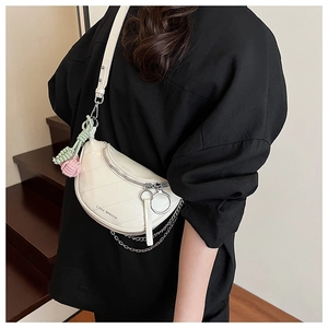 Detail of cream quilted half-moon crossbody bag with silver chain and woven knot charm