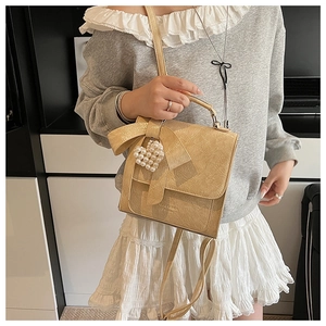 Detail of apricot bow shoulder bag with pearl heart pendant and pleated texture