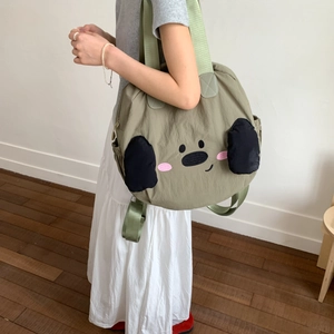 Detail view of a green nylon tote bag featuring a cute cartoon dog design and side pockets