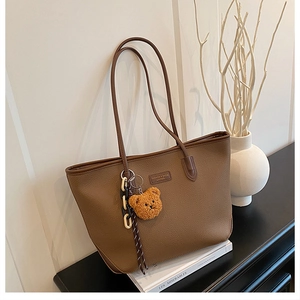 Dettaglio borsa tote in pelle marrone martellata con ciondolo orso e catena