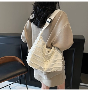 Detailed back view of a white canvas tote bag with unique fringe and wide strap