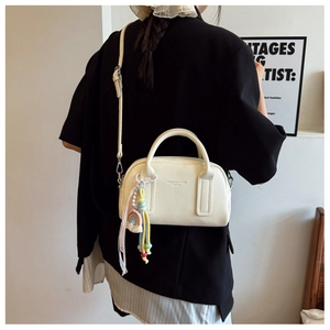 Detail of cream lychee texture crossbody bag with rainbow charm on a black blazer