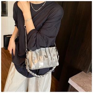 Detail of silver pleated dumpling bag featuring metallic texture and dual chain straps
