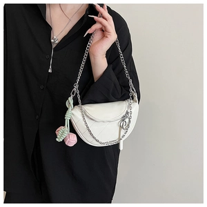 Detailed close-up of white saddle bag with silver chain strap and colorful woven charm