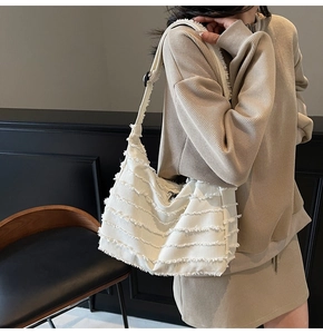 Detail of white canvas tote bag featuring horizontal fringe and wide shoulder strap style