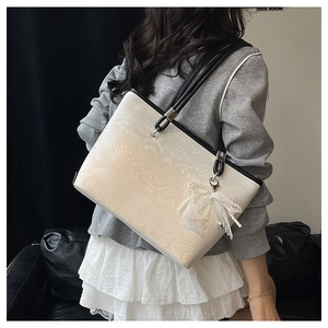 Off-white large tote bag with snake texture, black handles, and pearl bow charm detail