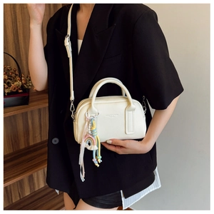 Detailed view of cream PU leather pillow bag featuring colorful rainbow tassel charm