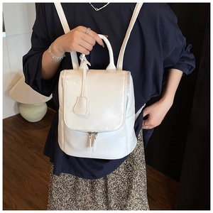 Detail of white glossy leather backpack with double zippers and elegant side charm