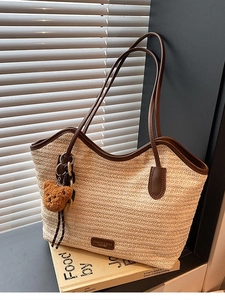 Large beige woven straw tote bag with brown leather handles and cute bear charm
