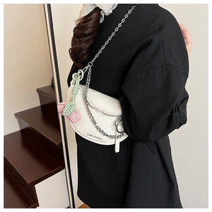 Detail of white quilted saddle bag with silver chain and braided rope tassel charm