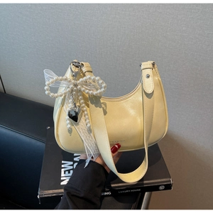 Detail der cremefarbenen Hobo-Tasche mit Perlbogen, Herzanhänger und Glanzfinish