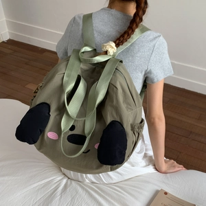 Detail of olive green nylon backpack featuring cute cartoon embroidery and soft 3D ears