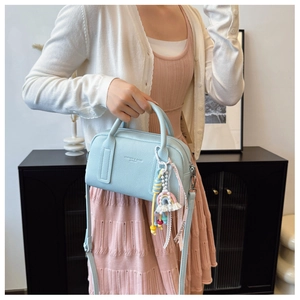 Detail of light blue pebble leather boston bag with a rainbow tassel and model styling