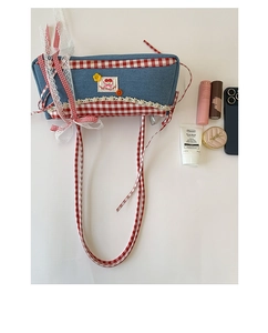 Flat lay of denim shoulder bag with red plaid trim, cherry patches and lace details