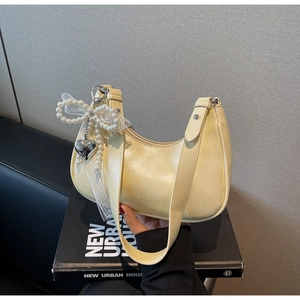 Detail der hellgelben Halbmond-Tasche mit Perlen-Schleife und Herzanhänger aus Metall