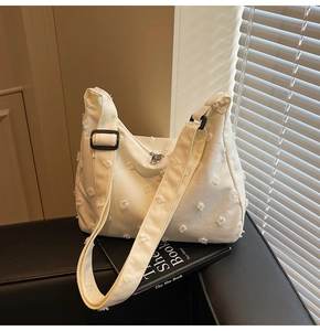 Detail view of large canvas tote bag featuring 3D pom-pom texture and adjustable strap