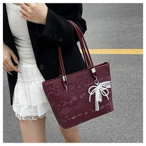 Macro detail of wine red snake pattern tote bag with lace pearl bow charm