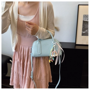 Detail of light blue pebble leather bag with rainbow charm and fashion text ribbon