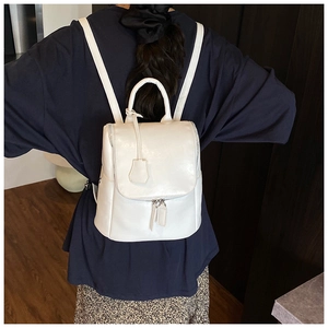 Detailed back view of a minimalist white faux leather backpack on a model's outfit
