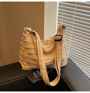 Detail of light beige fringed canvas tote bag with adjustable black strap and silver zipper