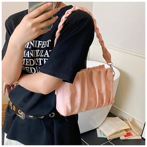 Detailed view of pink pleated handbag with woven shoulder strap and soft fabric texture
