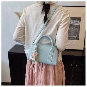 Detail of light blue lychee texture bag featuring rainbow charm and metallic hardware