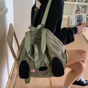 Detail of olive green nylon tote bag featuring a cute cartoon face and durable straps