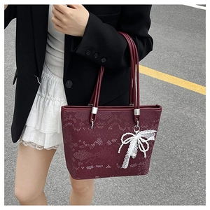Detail of burgundy snakeskin tote bag with a lace bow pendant and pearl accent
