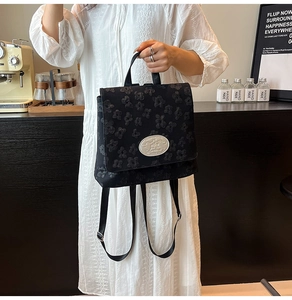 Detailansicht eines schwarzen Jacquard-Reiserucksacks mit floraler Textur und Emblem