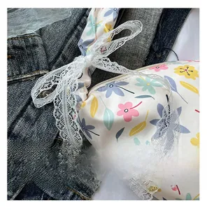 Detail of floral Oxford fabric bag featuring white lace bow and metal zipper closure
