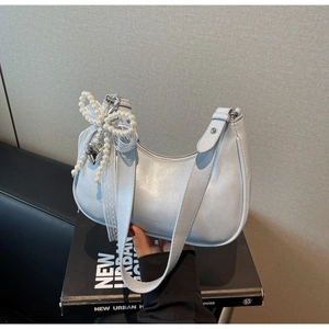 Detail der hellblauen Halbmond-Tasche mit Metallic-Finish und Perlen-Schleifen-Anhänger