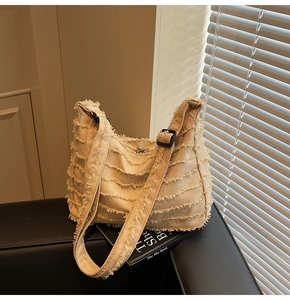 Detail of beige canvas tote featuring unique layered raw edge wave texture and black buckle