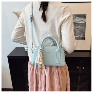 Detail of light blue lychee leather boston bag with rainbow tassel and shoulder strap