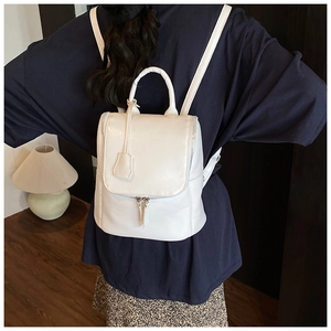 Close-up of a white leather backpack with top handle and silver metal zipper detail