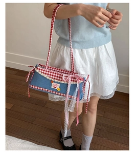 Detail of blue denim shoulder bag with red gingham trim and white lace embroidery