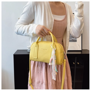 Detail of yellow boston bag with lychee texture and rainbow tag in a lifestyle setting