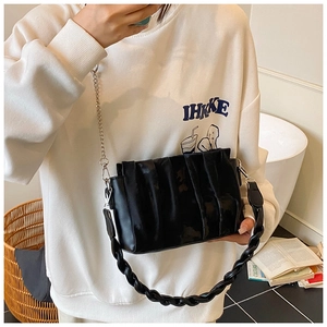 Detail of black pleated shoulder bag featuring a silver chain and thick woven handle