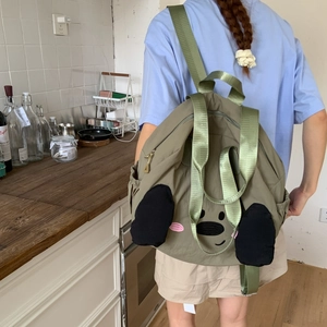 Close-up of green nylon backpack with cartoon embroidery and side elastic pocket