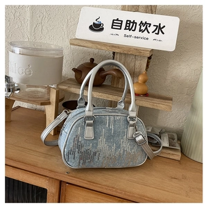 Detail of blue denim sequins handbag with silver leather handles and zip closure