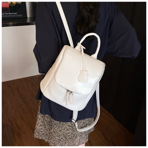 Detail of a creamy white leather backpack with double metal zippers and a top flap design